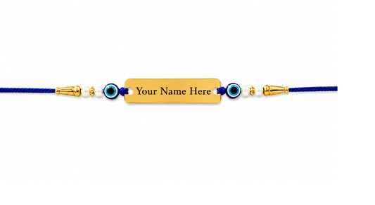 A personalized blue cord bracelet with gold-toned metal accents, evil eye beads, and a central gold rectangular plate engraved with 'Your Name Here'.