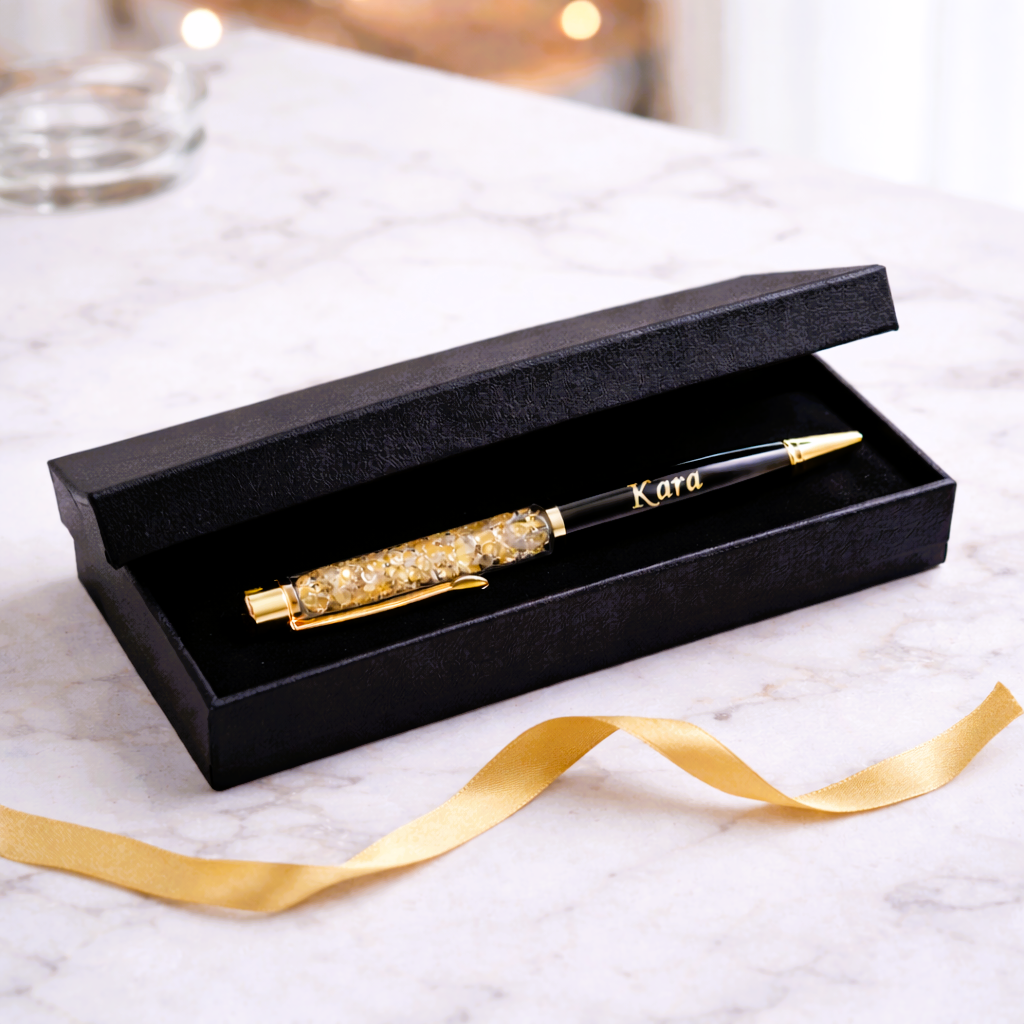 Personalized black and gold crystal pen in a gift box on marble surface with gold ribbon