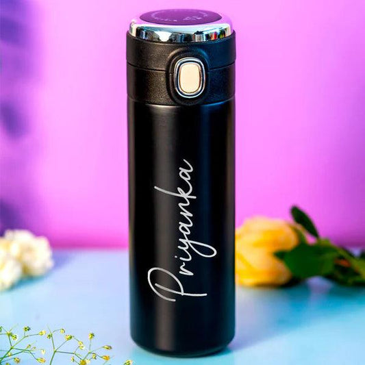 Black personalized water bottle with temperature display, name 'Priyanka', on pastel background